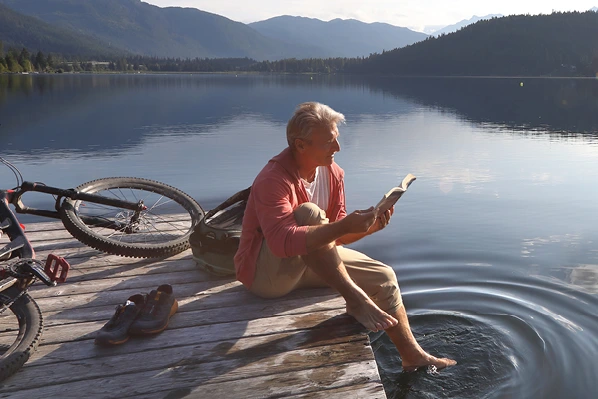 A man reading a book on a dock